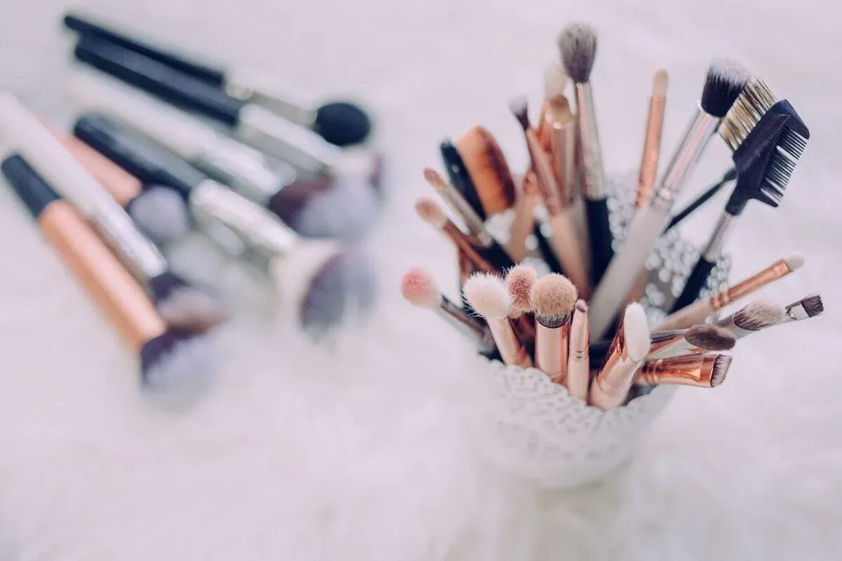 Makeup brushes in a white holder, with more brushes lying on a fluffy white rug