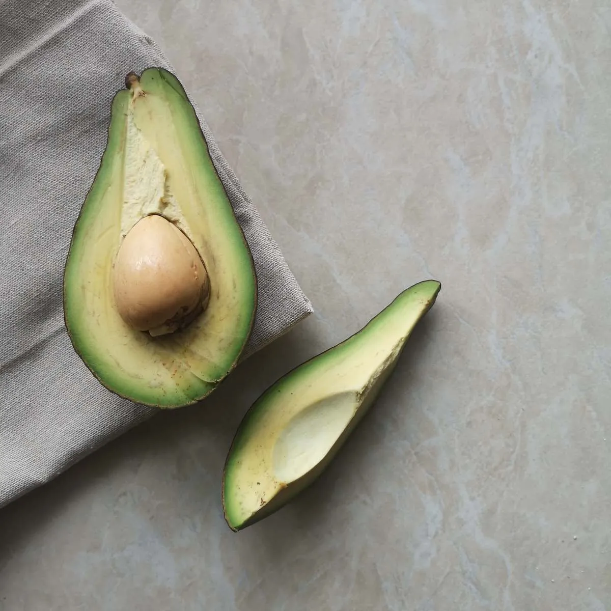 Demi-avocat avec son noyau et une moitié sans noyau sur un fond de marbre