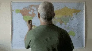 A gray-haired man pins a world map, then the view zooms to the US East Coast