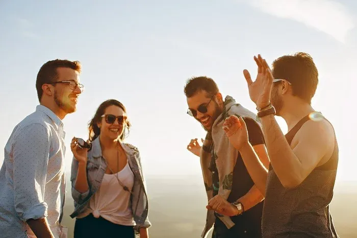 Groupe d'amis souriants qui rient en plein air au soleil couchant