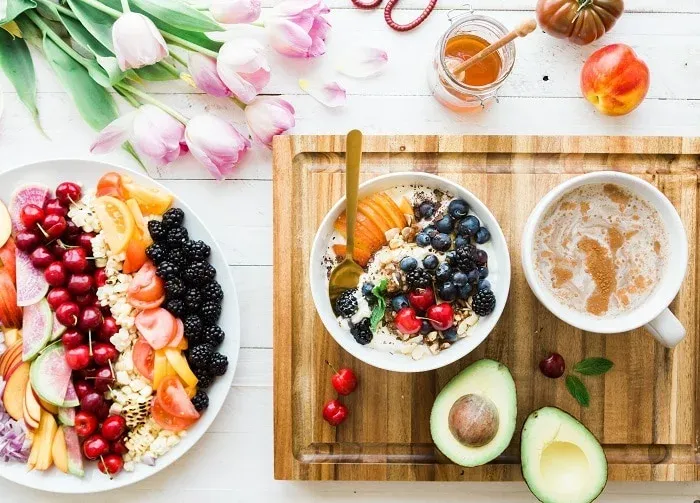 Assiette de fruits, bol de céréales aux baies, tasse de café et avocat