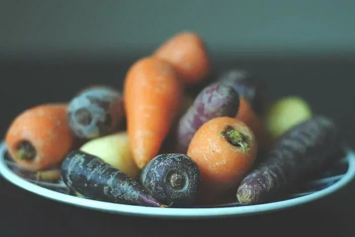 Carottes orange, violettes et jaunes dans une assiette
