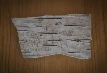A strip of birch bark scratched with Cyrillic letters and a stick figure